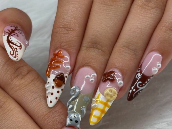 Long almond nails in a fall mix: a brown branch painted on white, white polka dots under a raised orange leaf, a small raised grey cat on sage, yellow plaid with a raised charm and a brown tip with white swirls, with tiny pearls, over white fur.