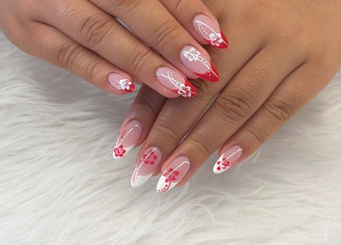 Almond Gel X nails with red and white French tips and hand painted hibiscus flowers, hands crossed over white fur.